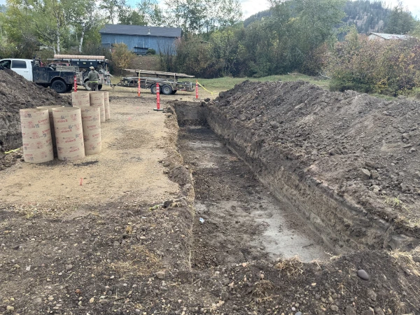 The footing trench excavated, with Sonotube forms staged on the pad area waiting to be set.